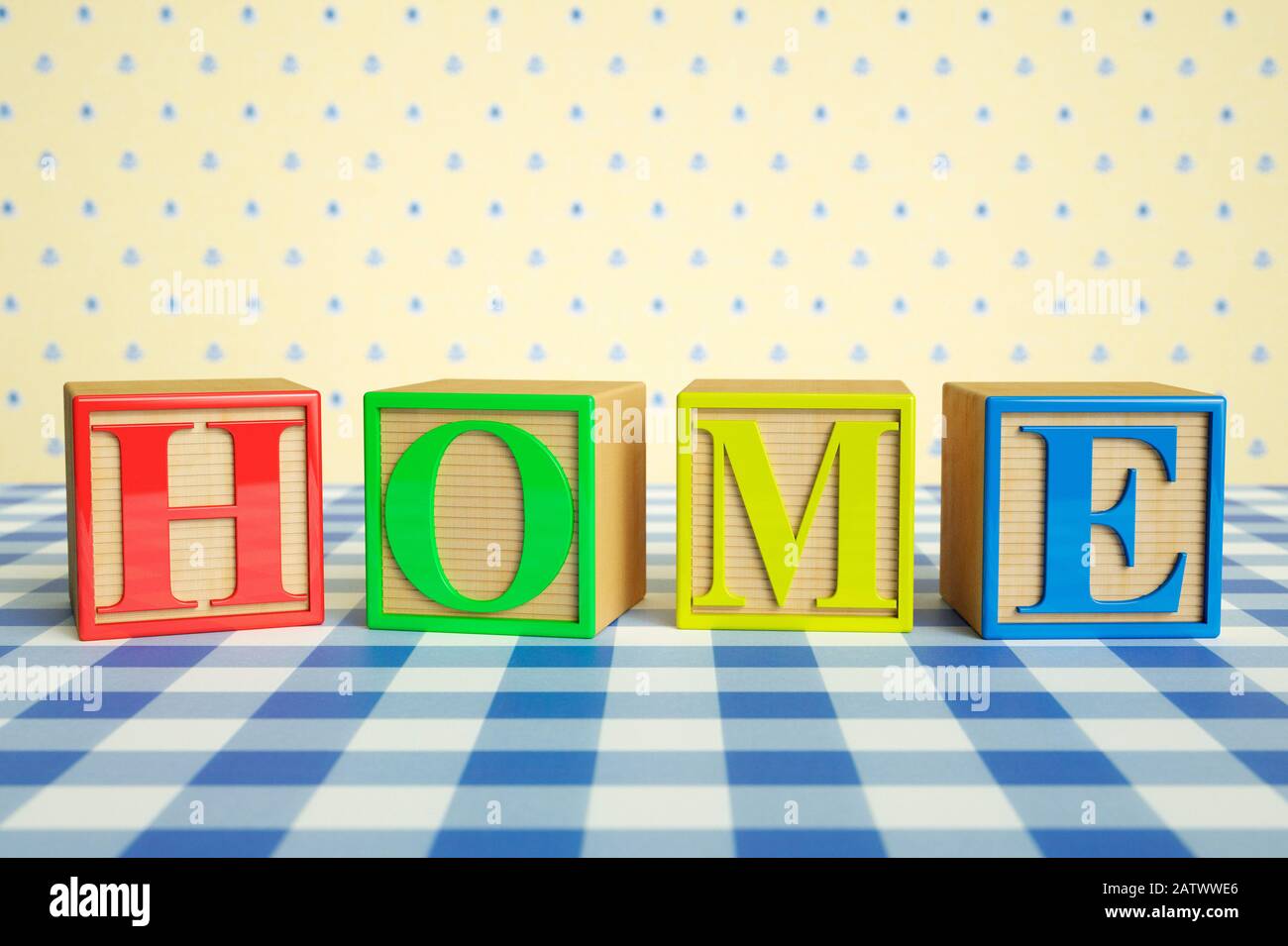 Childrens wooden ABC blocks spelling HOME on a checked tablecloth Stock Photo