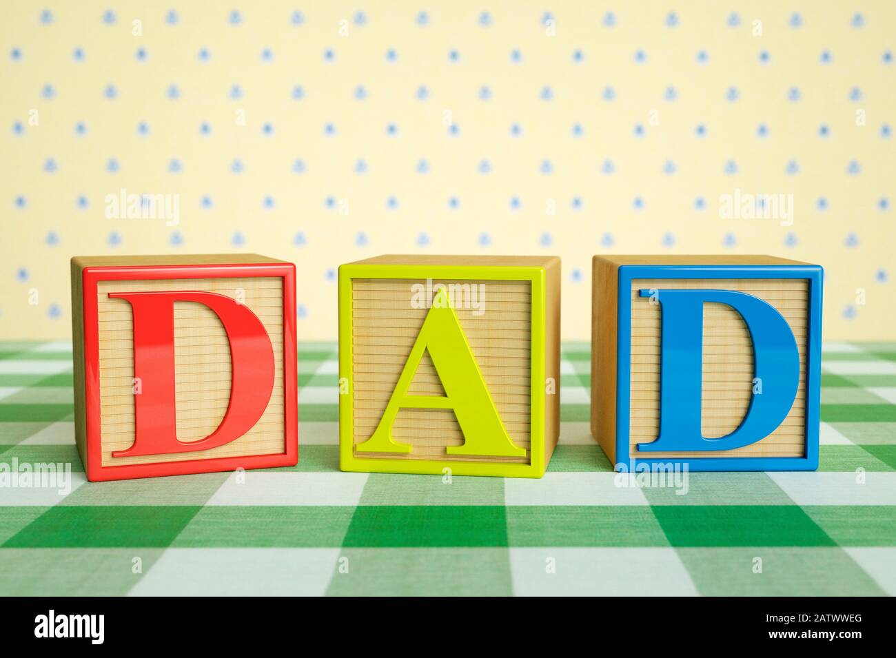 Childrens wooden ABC blocks spelling DAD on a checked tablecloth Stock Photo