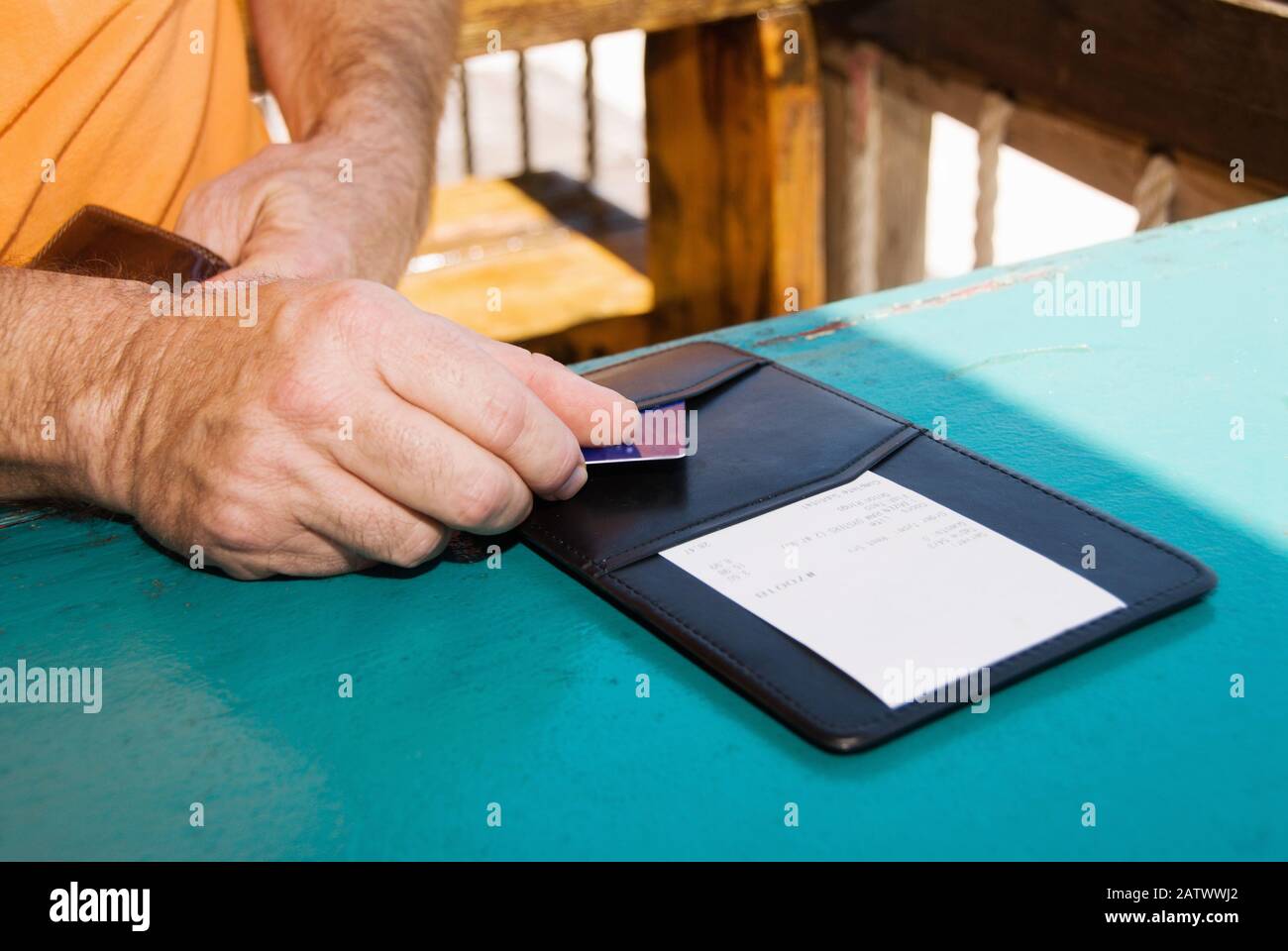A man is paying the lunch bill with a charge card at a restaurant.  This was shot on a restaurant patio outdoors. Selective focus. Stock Photo
