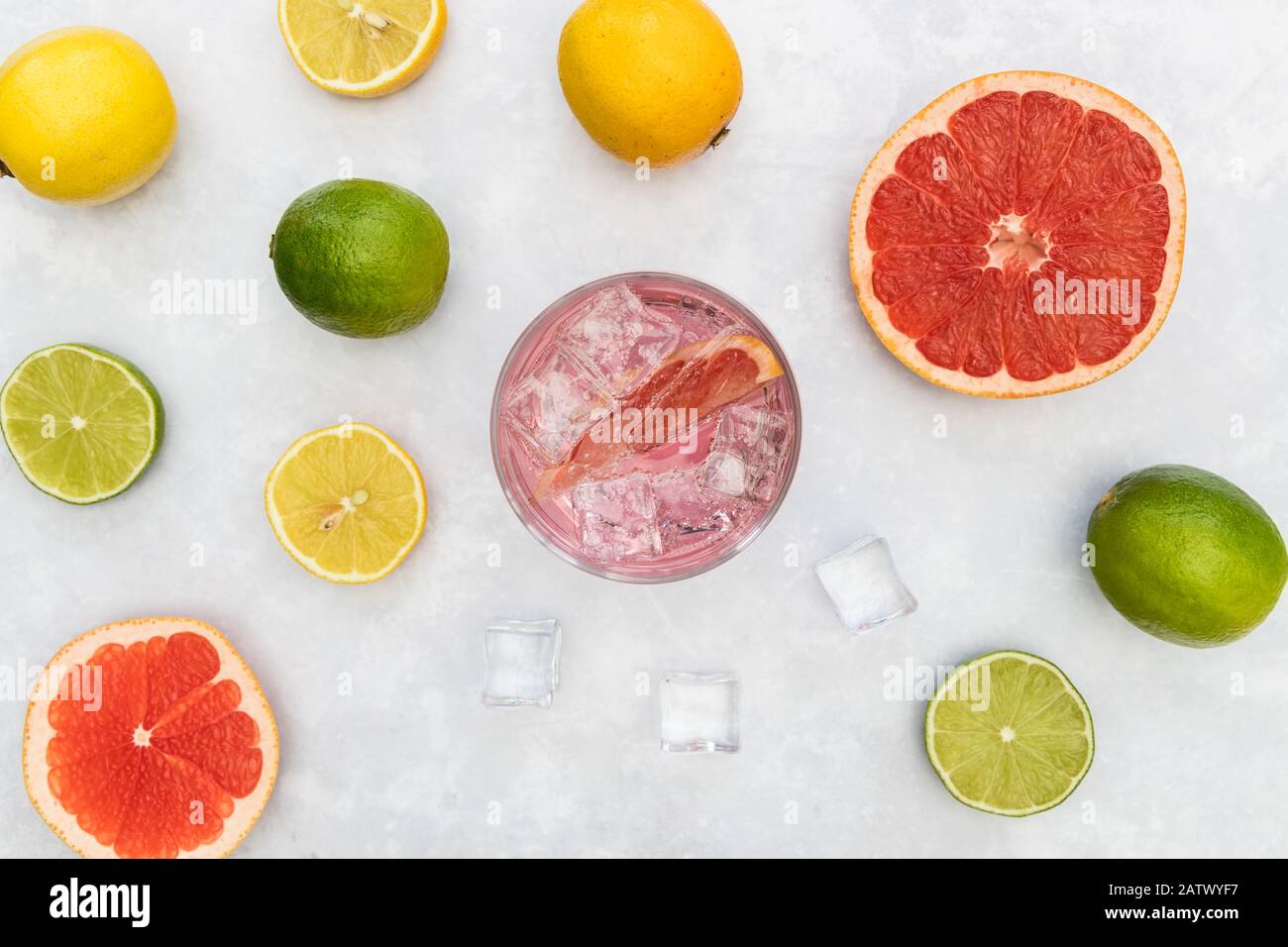 Pink gin tonic vodka soda fruit grapefruit cocktail drink in glass with ice, top view on white