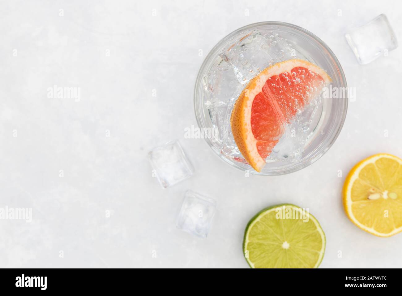 Pink gin tonic vodka soda fruit grapefruit cocktail drink in glass with ice, top view on white