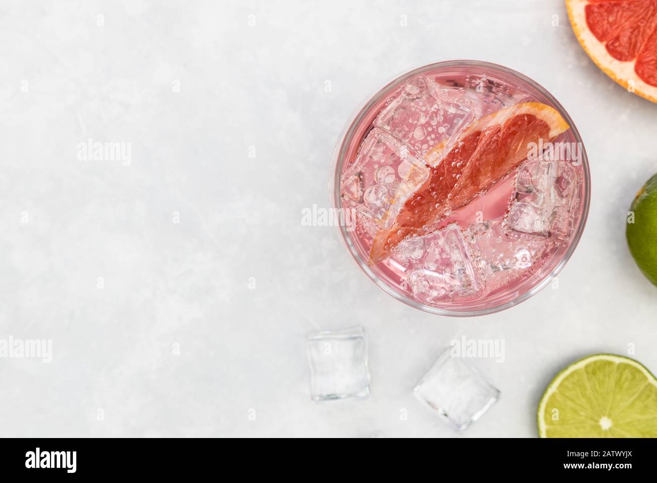 Pink gin tonic vodka soda fruit grapefruit cocktail drink in glass with ice, top view on white