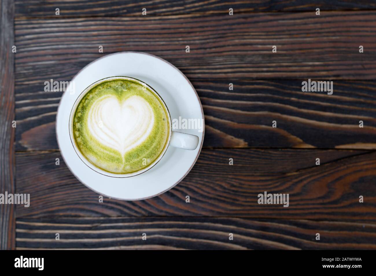 Green matcha tea latte in a white cup on brown wooden background isolated Stock Photo