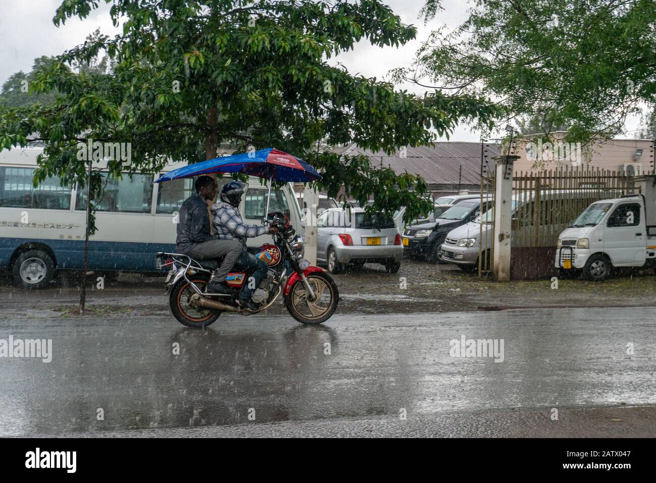 Arusha, Tanzania - 15 Jan 2020: Motorcycle with umbrella - feature of Arusha. People on the street in Arusha city, Tanzania Stock Photo