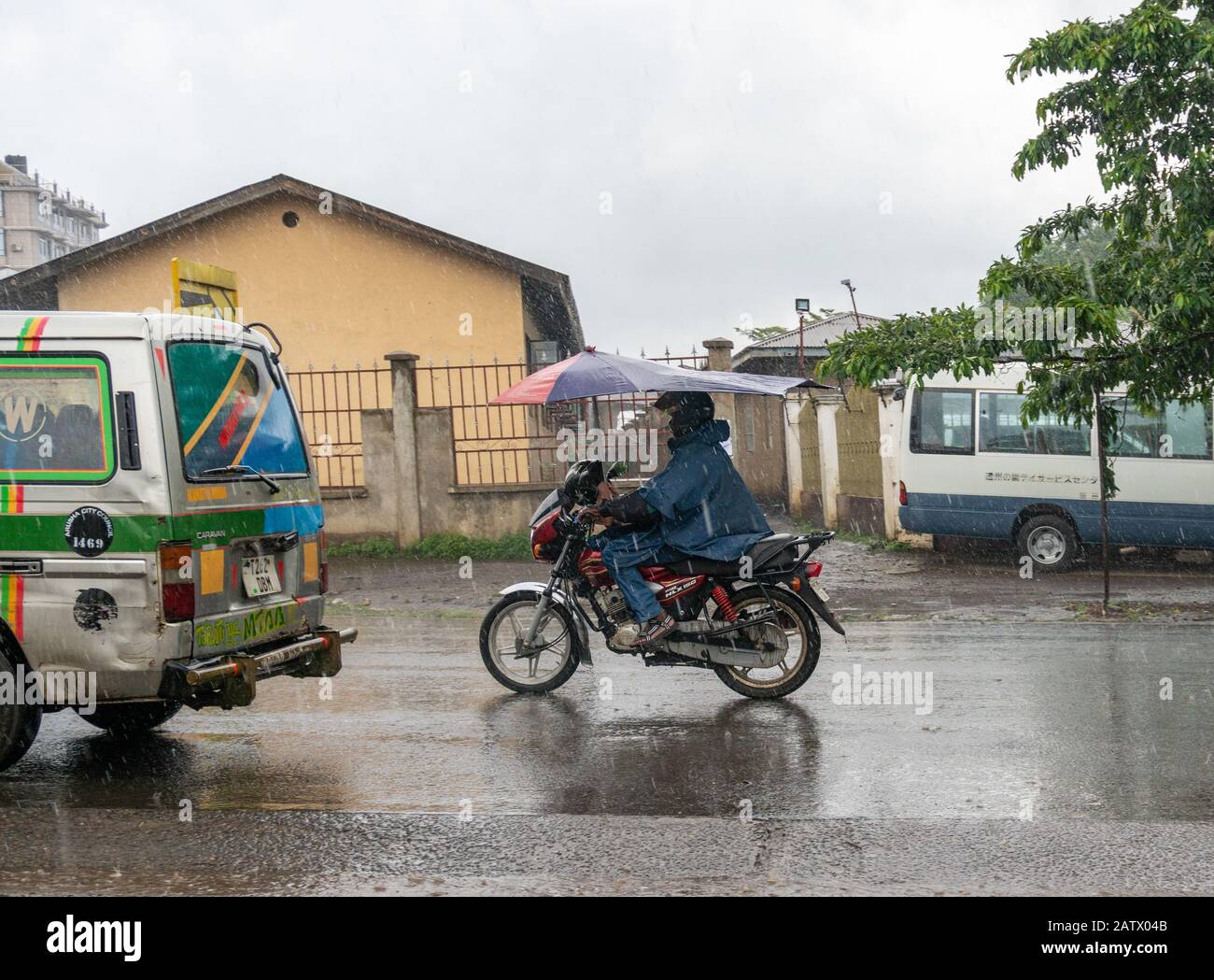 Arusha, Tanzania - 15 Jan 2020: Motorcycle with umbrella - feature of Arusha. People on the street in Arusha city, Tanzania Stock Photo