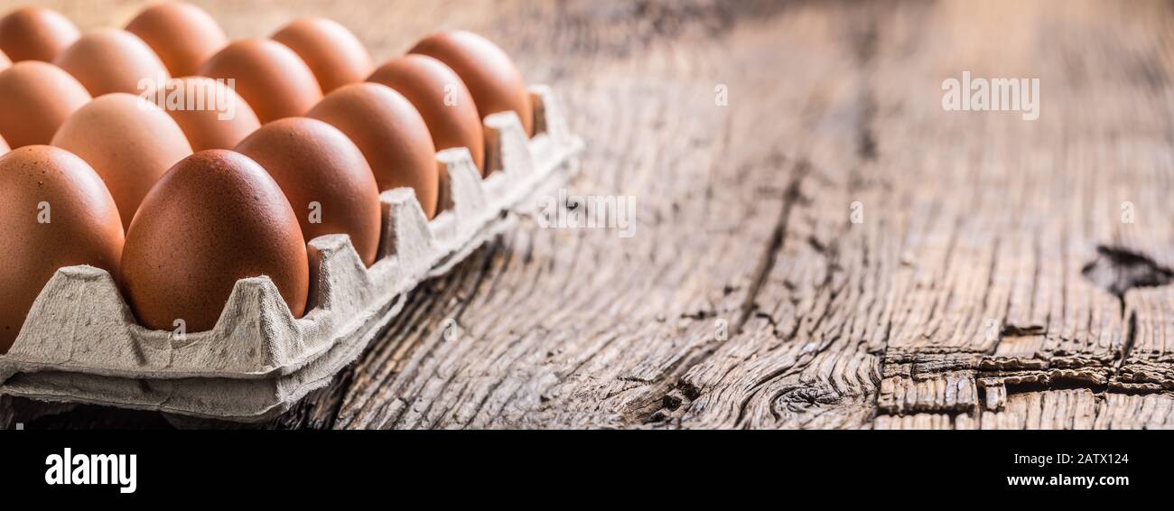 Chicken eggs in carton box on rustic wooden table Stock Photo