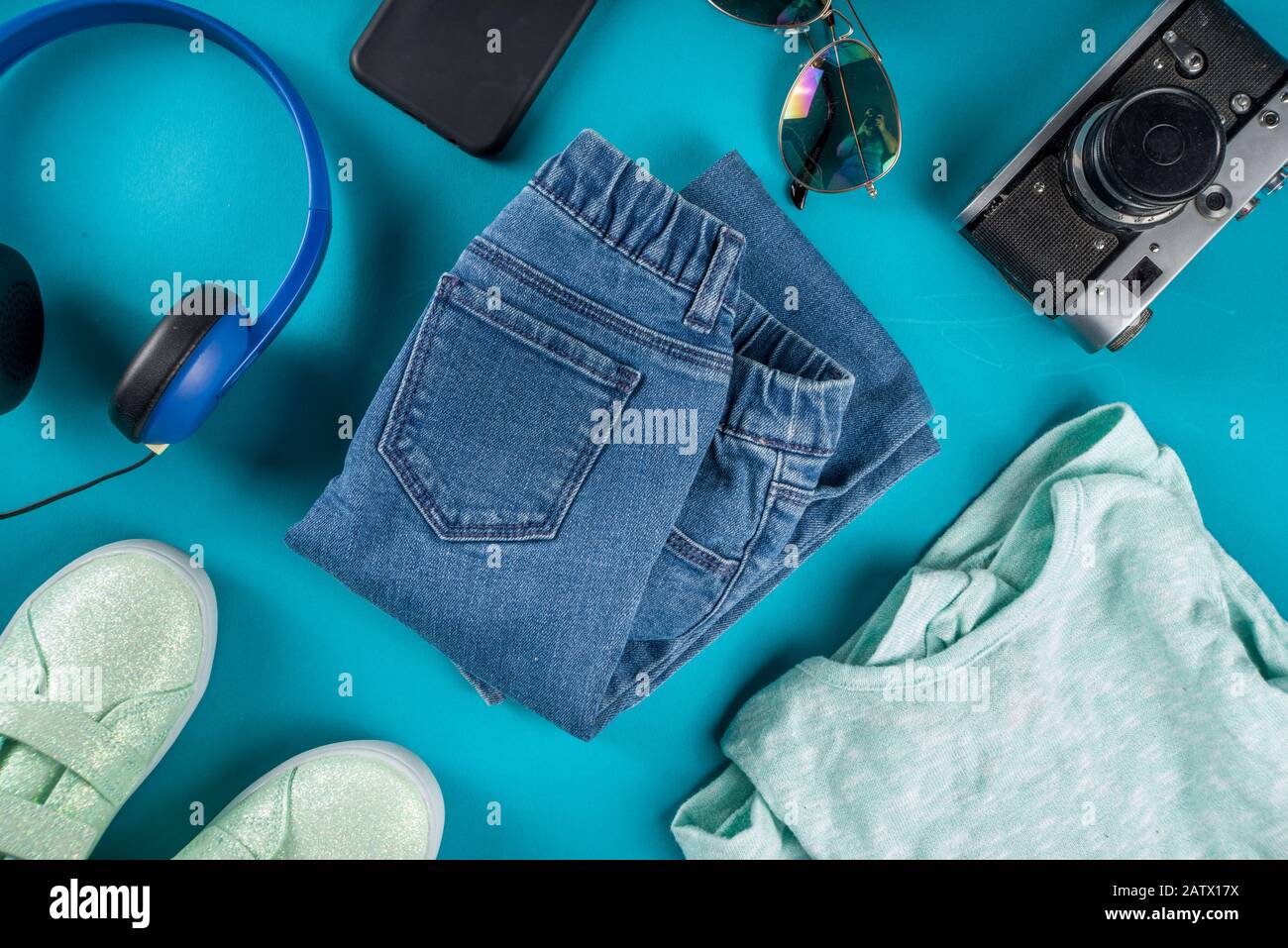 Stylish female spring autumn outfit and accessories on turquoise blue background, flat lay. Trendy girls clothes flatlay copy space top view Stock Photo