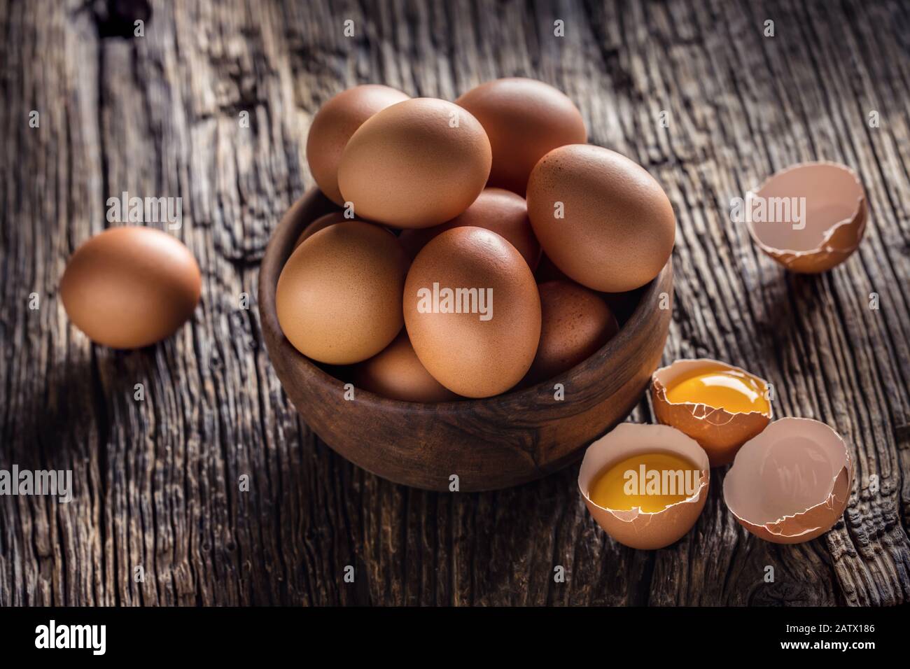 Chicken eggs in wooden bowl on rustic oak table Stock Photo