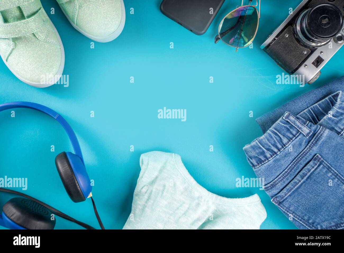 Stylish female spring autumn outfit and accessories on turquoise blue background, flat lay. Trendy girls clothes flatlay copy space top view Stock Photo
