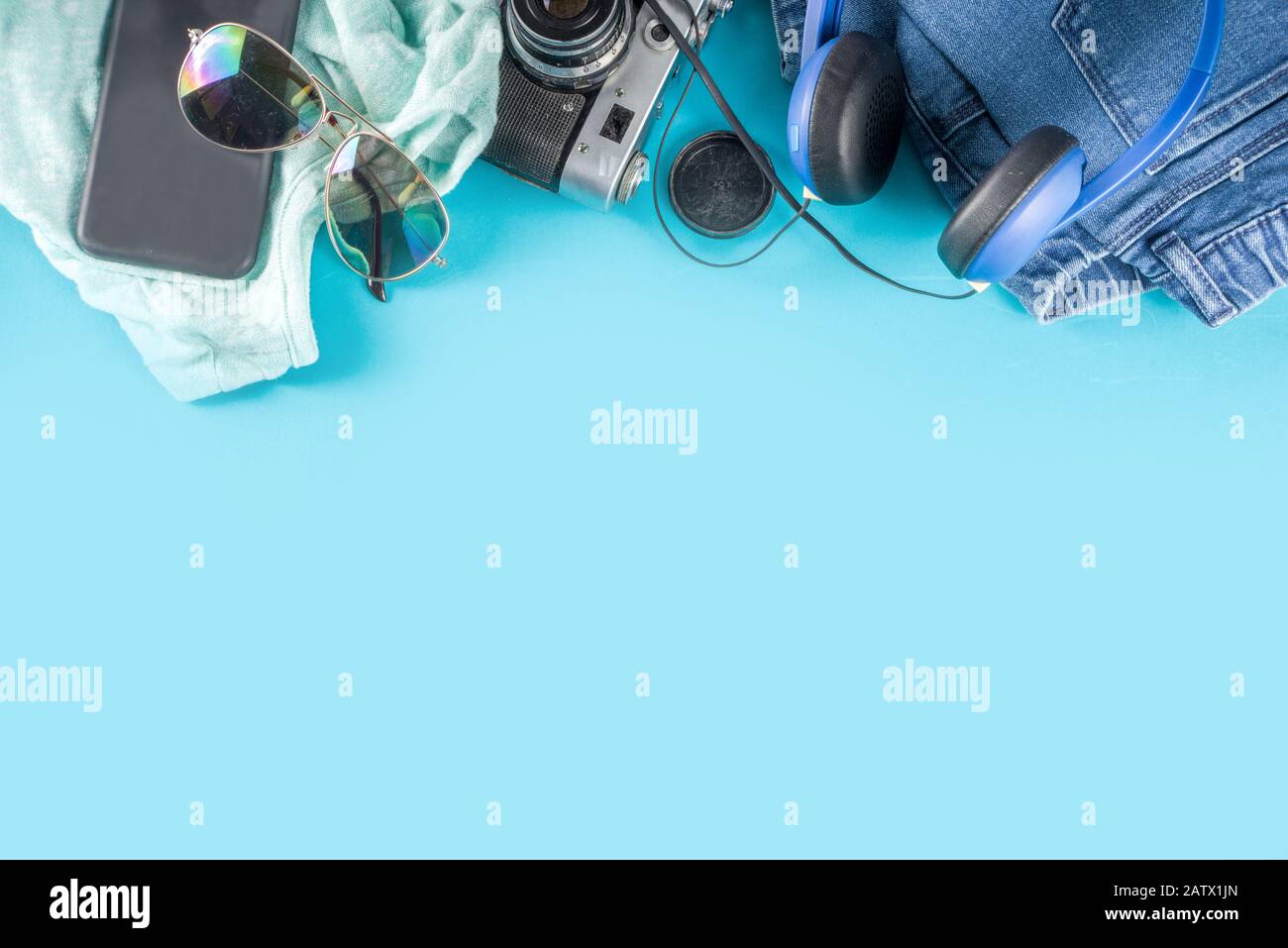 Stylish female spring autumn outfit and accessories on turquoise blue background, flat lay. Trendy girls clothes flatlay copy space top view Stock Photo