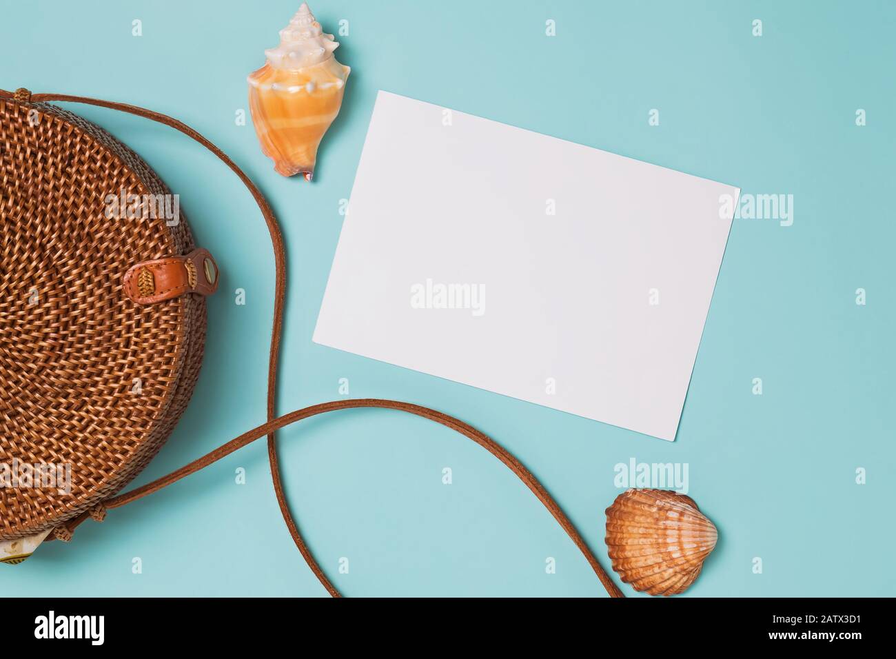 Seashells and ratan bag on blue background, top view. Summer vacation planning. Flat lay with empty paper, place for text Stock Photo