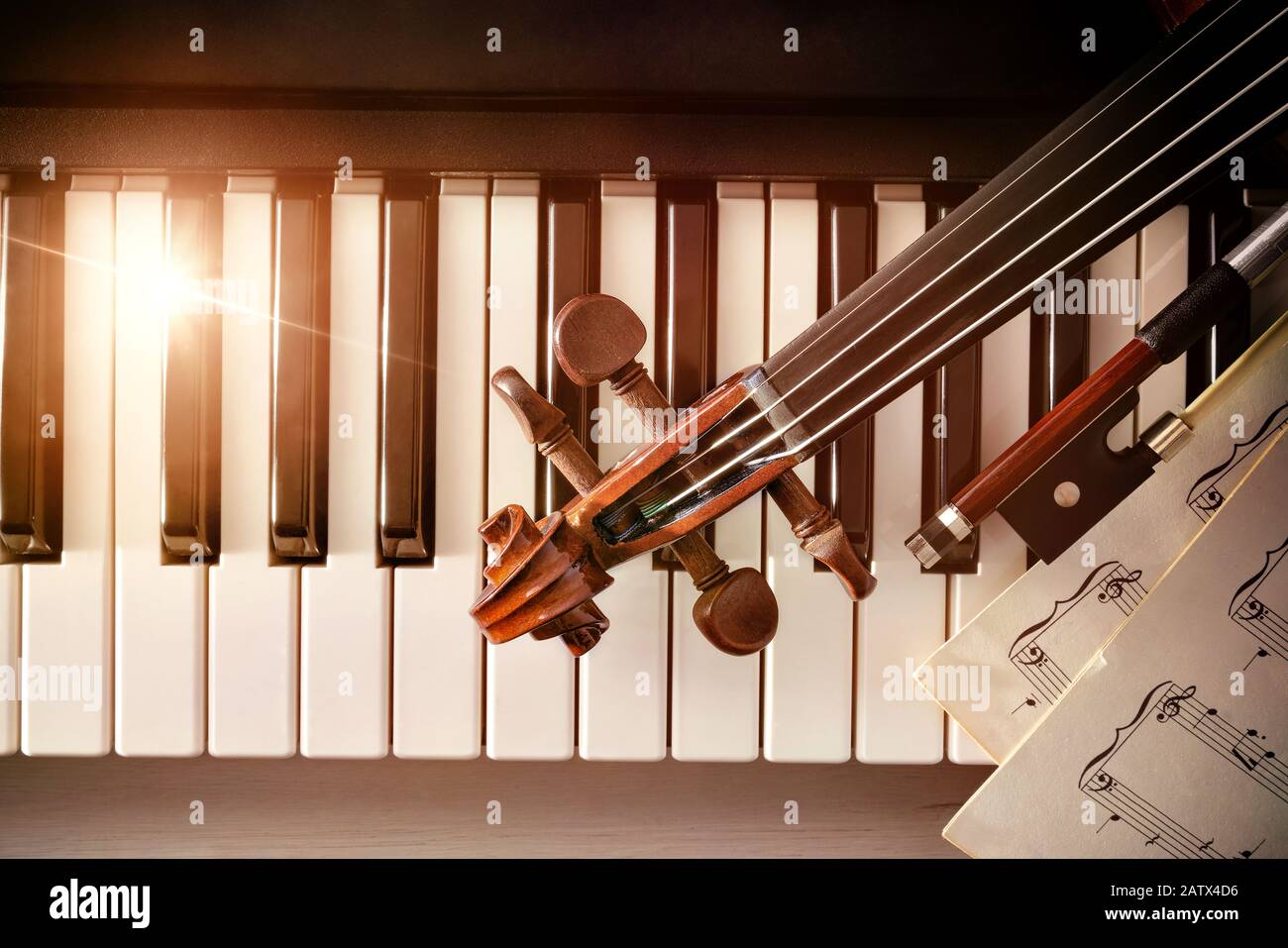 Violin pegbox bow and sheet music on piano keys. Concept of interpretation of piano music and string instruments. Top view. Horizontal composition. Stock Photo