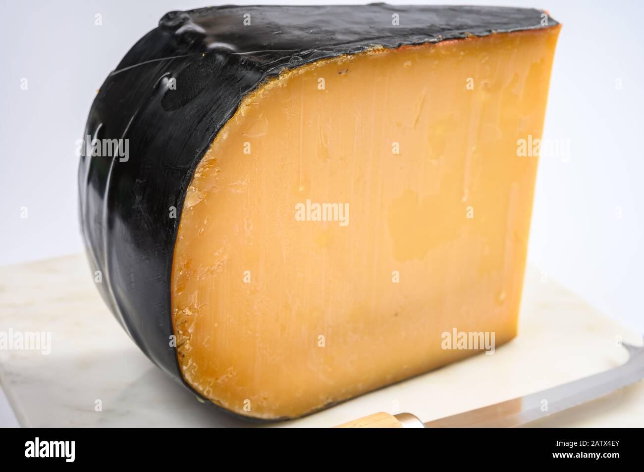 One piece of old Dutch gouda cheese with black wax close up Stock Photo