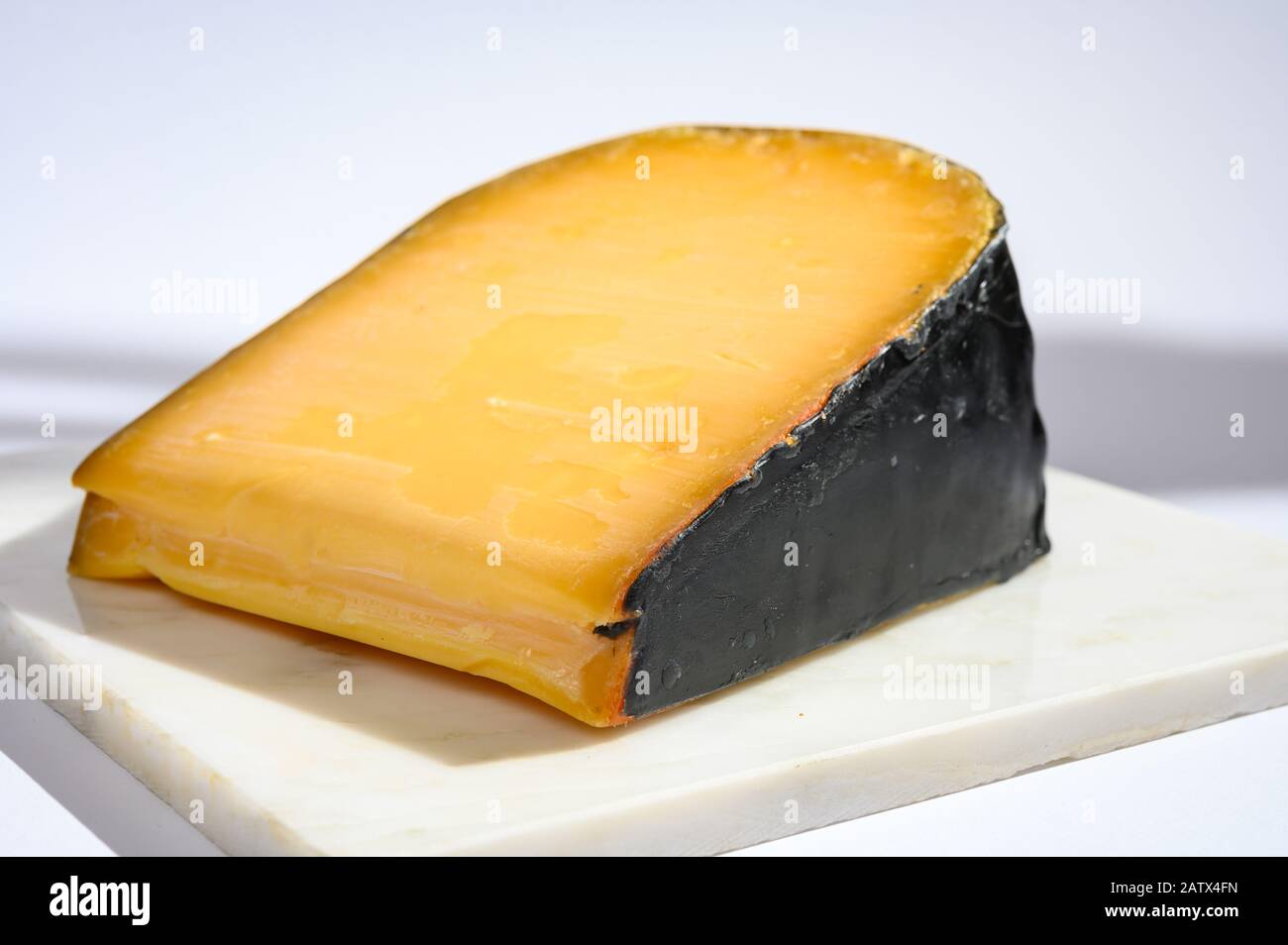 One piece of old Dutch gouda cheese with black wax close up Stock Photo
