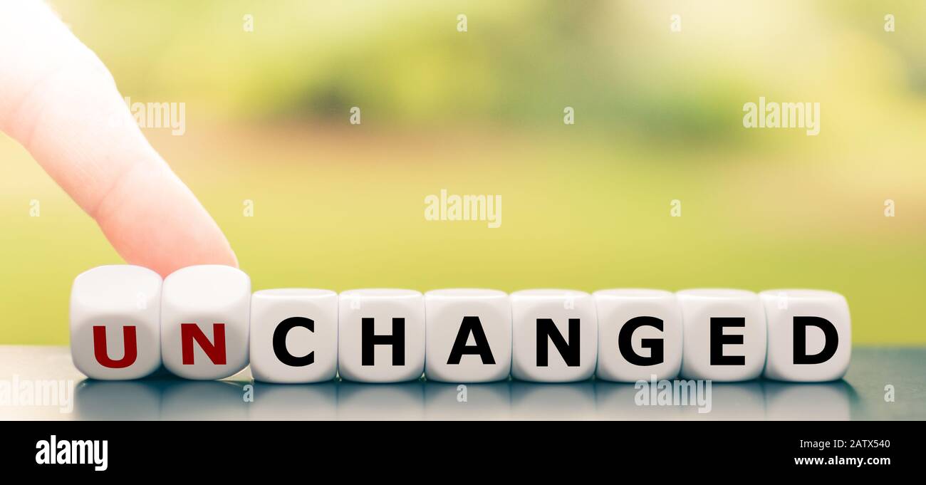 Hand turns dice and changes the word 'unchanged' to 'changed'. Stock Photo