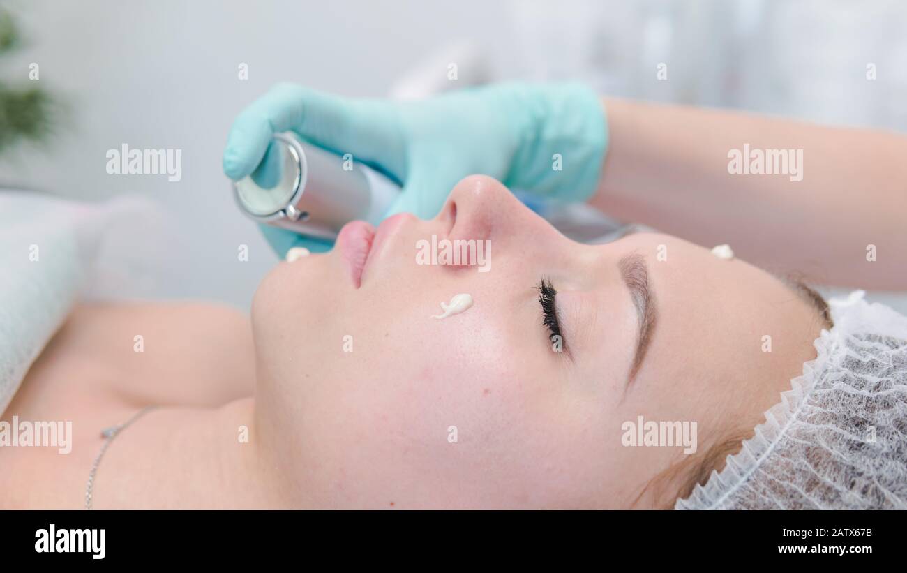 The female dermatologist do face massaged to beautiful girl cosmetology cabinet or beauty clinic. Concept of face cleanser, skin and health care Stock Photo