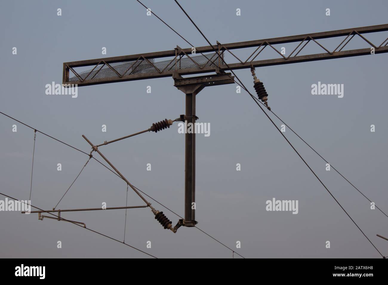 View of overhead electric lines used by train locomotives. Pole supporting the power lines used by electric train engines. Stock Photo