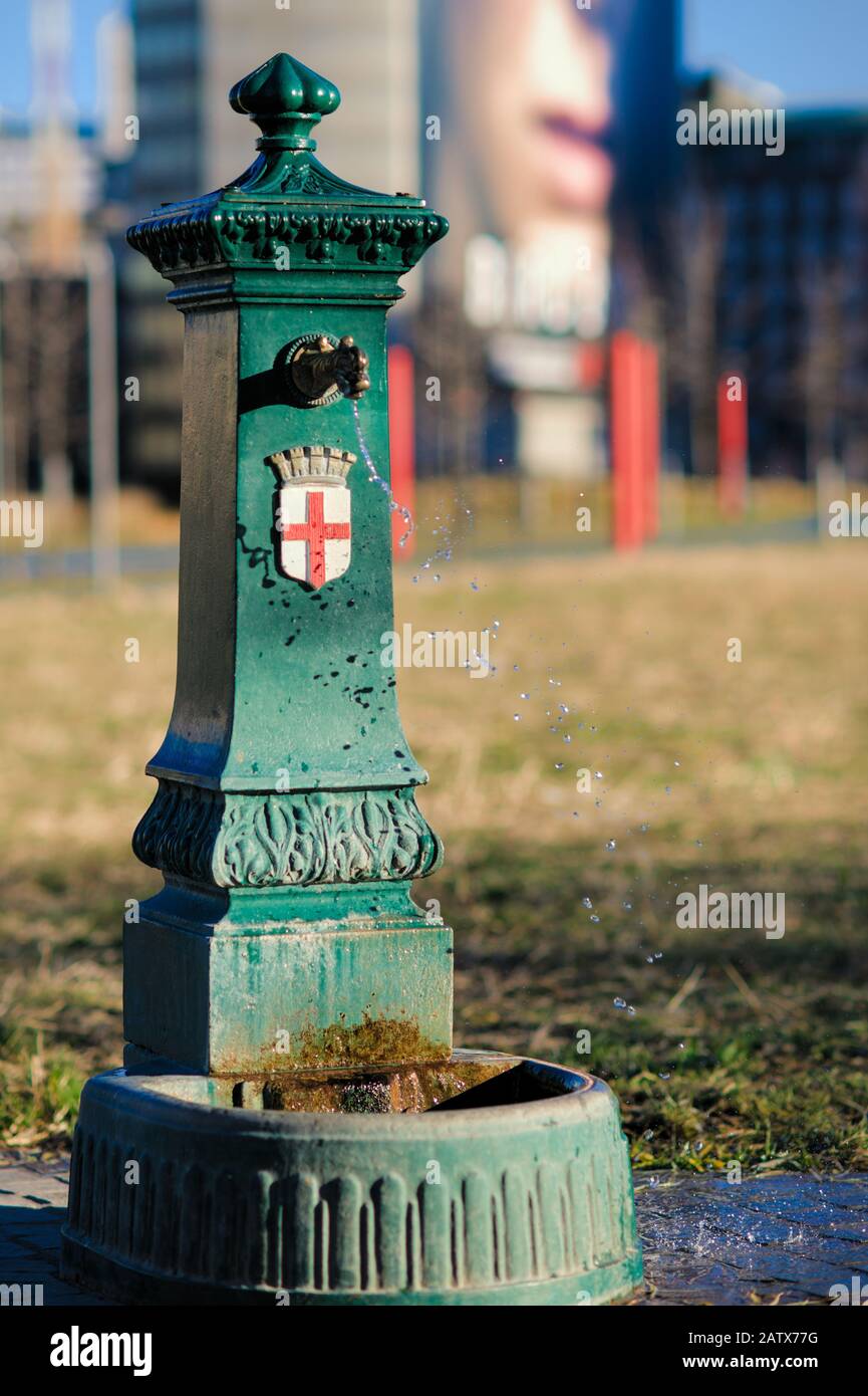 Public municipal fountain nicknamed Green Dragon with water sprayed by the wind in the public park Library of Trees, Milan, Italy Stock Photo
