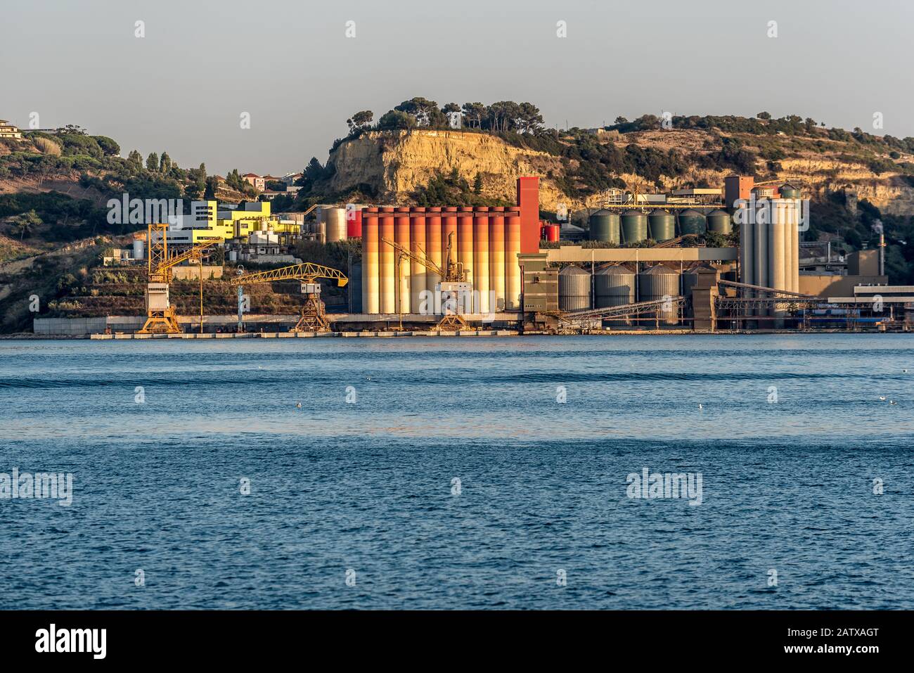 Colourful industrial silos at shipping terminal next to urban area on the Tejo River in Portugal in afternoon sunshine Stock Photo