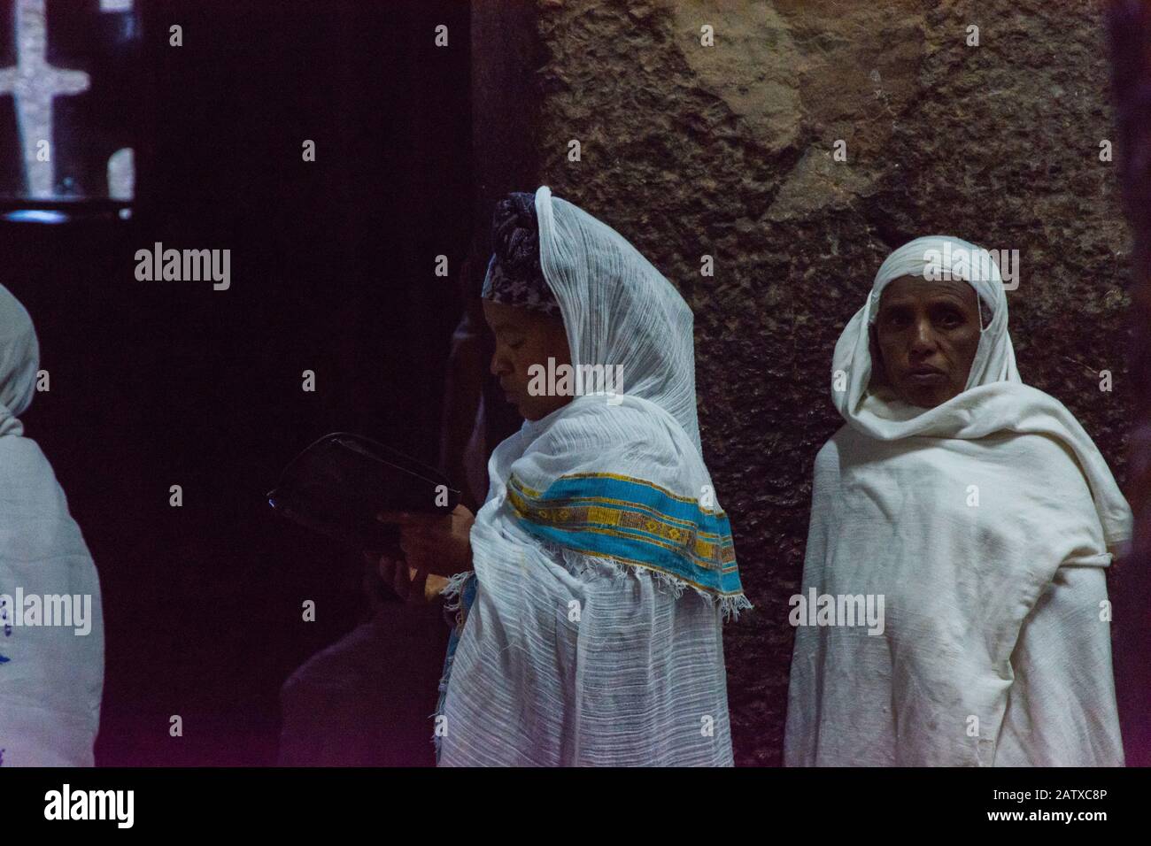 Lalibela, Ethiopia - Nov 2018: People dressed up in white traditional ethiopian clothes praying in interior of the the rock excavated church in Lalibe Stock Photo