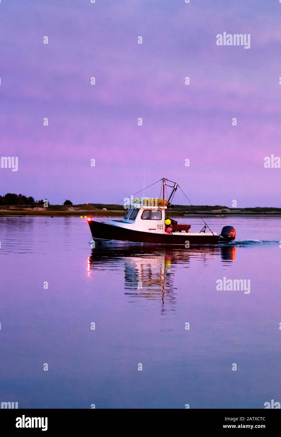 Fishing boat returns to harbor at sunset. Stock Photo