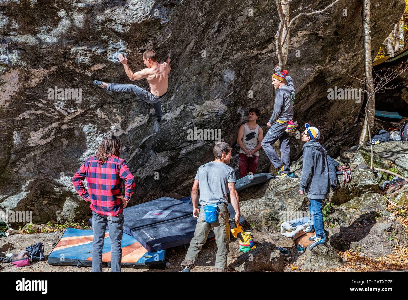 Guys practice rock climbing on natural boulder at Smuggler's Notch State Park. Stock Photo