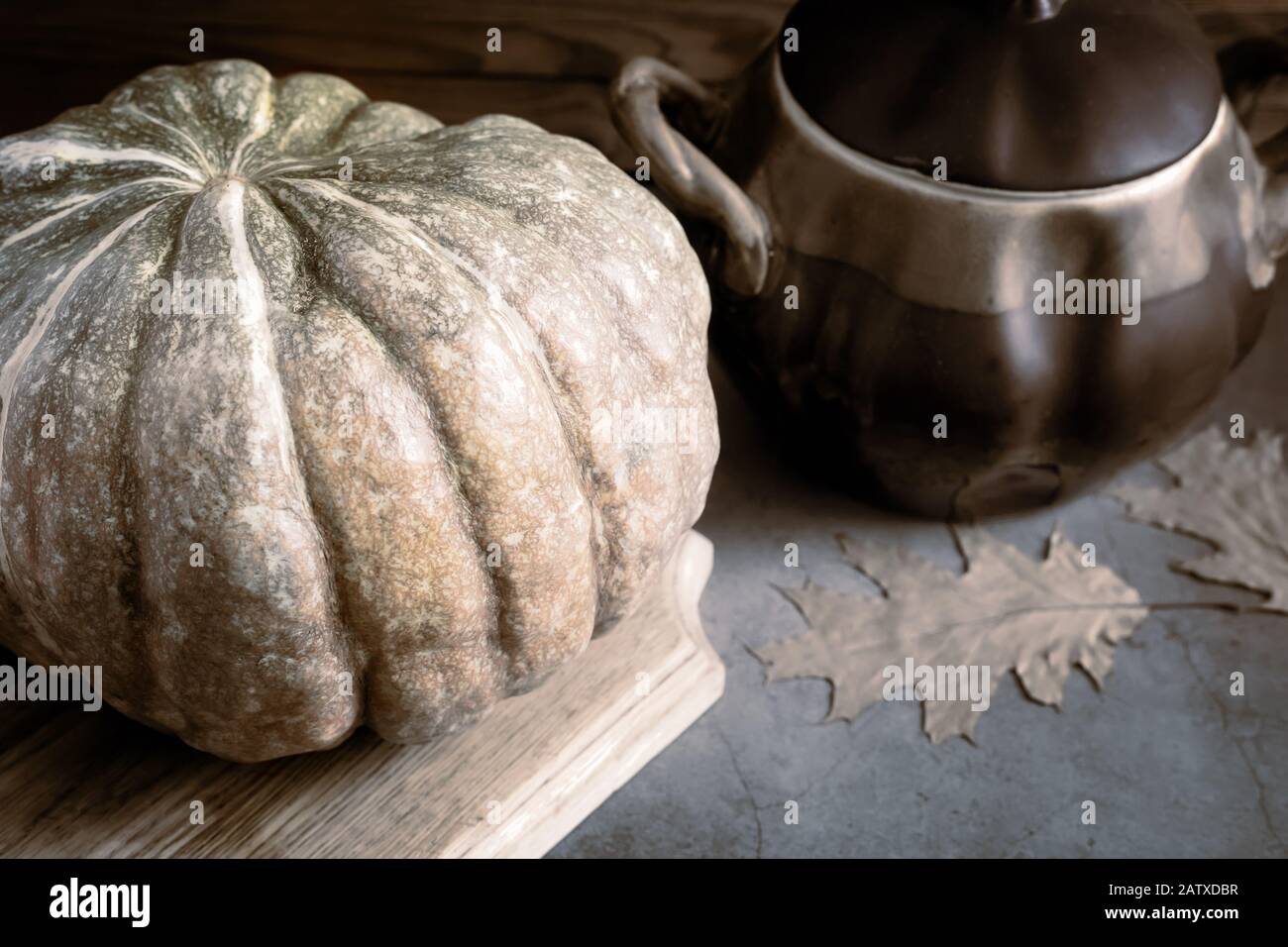 A large pumpkin next to a ceramic pot Stock Photo