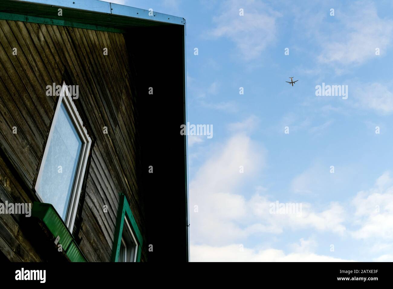 Airplane flying above old house Stock Photo