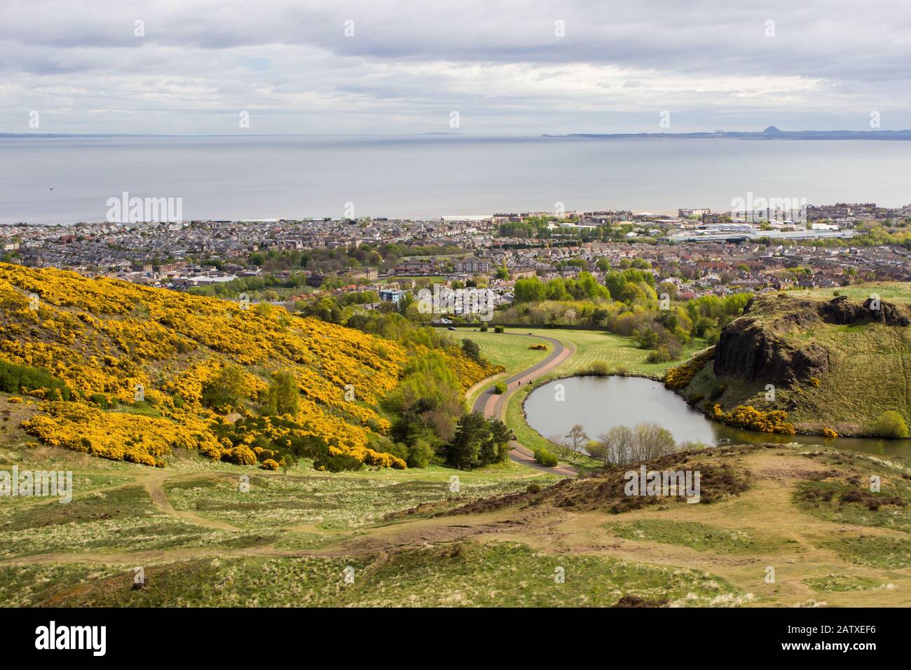 A view from Arthurs Seat over the Dunsappie Loch in Holyrood Park, Edinburg, with a partial view of the Firth of Forth and Leith in the Background Stock Photo