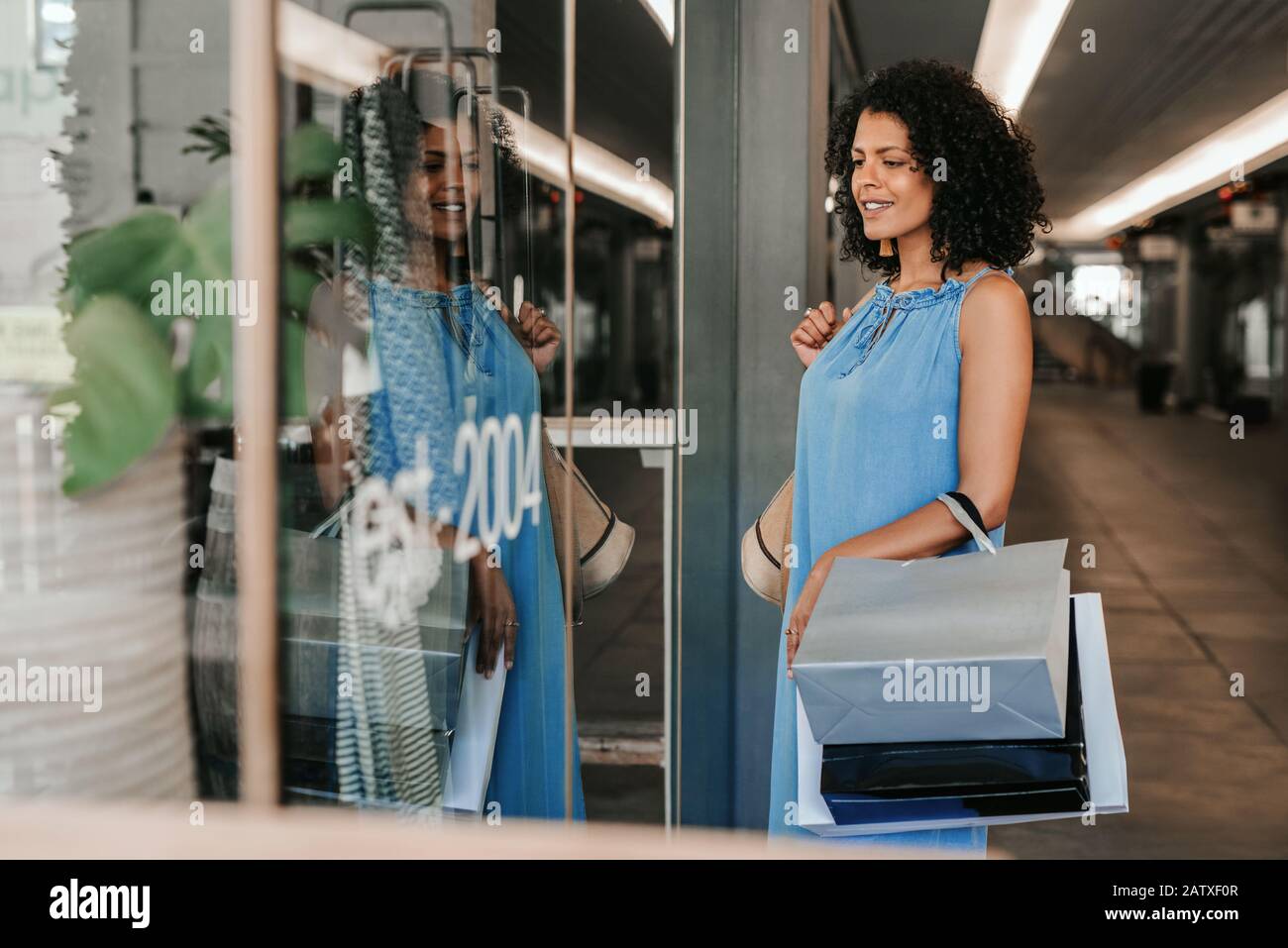Smiling young woman window shopping in a mall Stock Photo