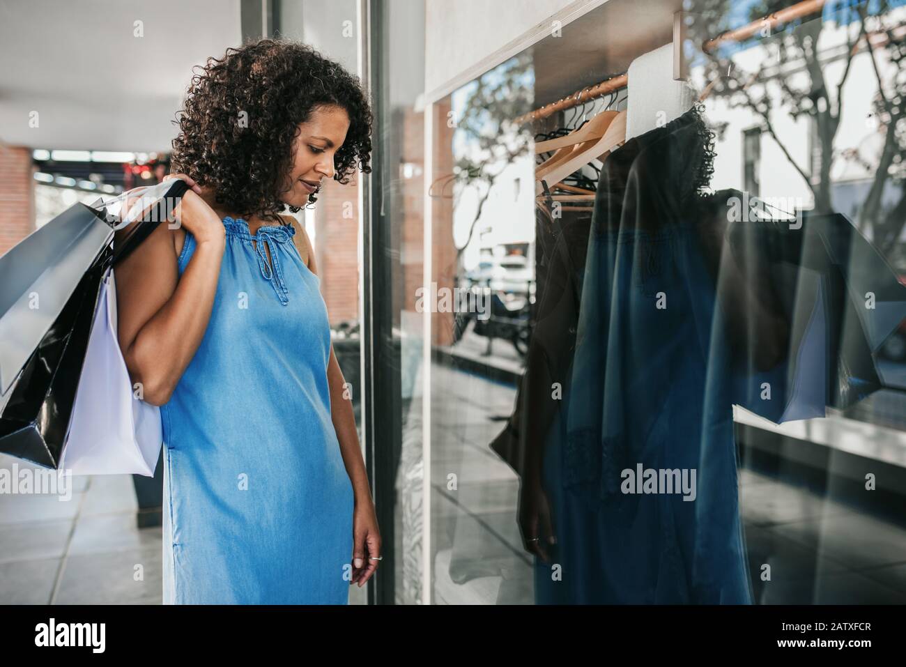 Smiling woman looking at clothing in a boutique window Stock Photo