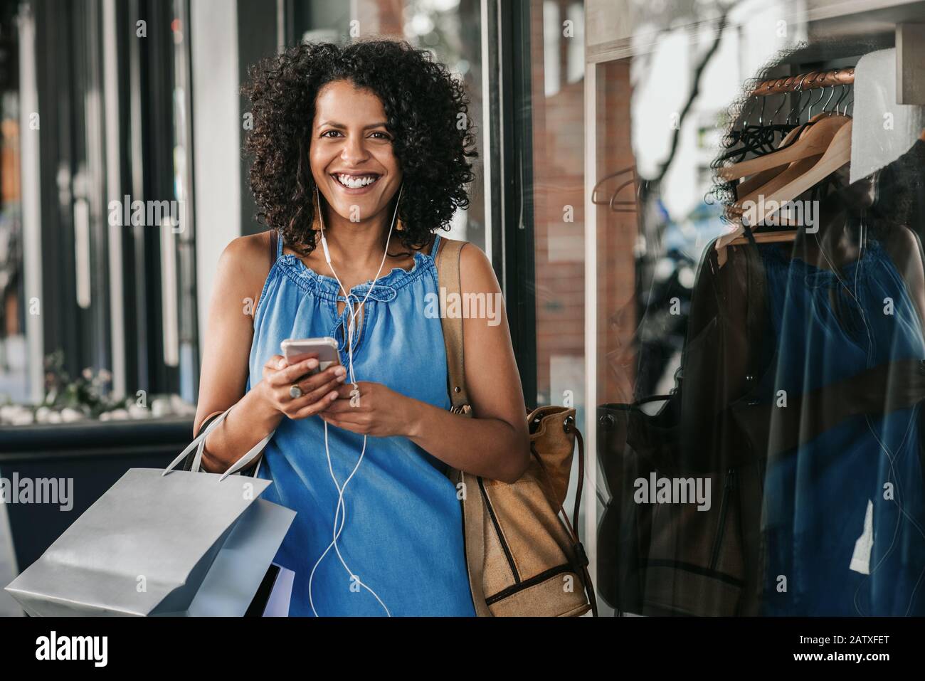 Smiling woman listening to music while out clothes shopping Stock Photo
