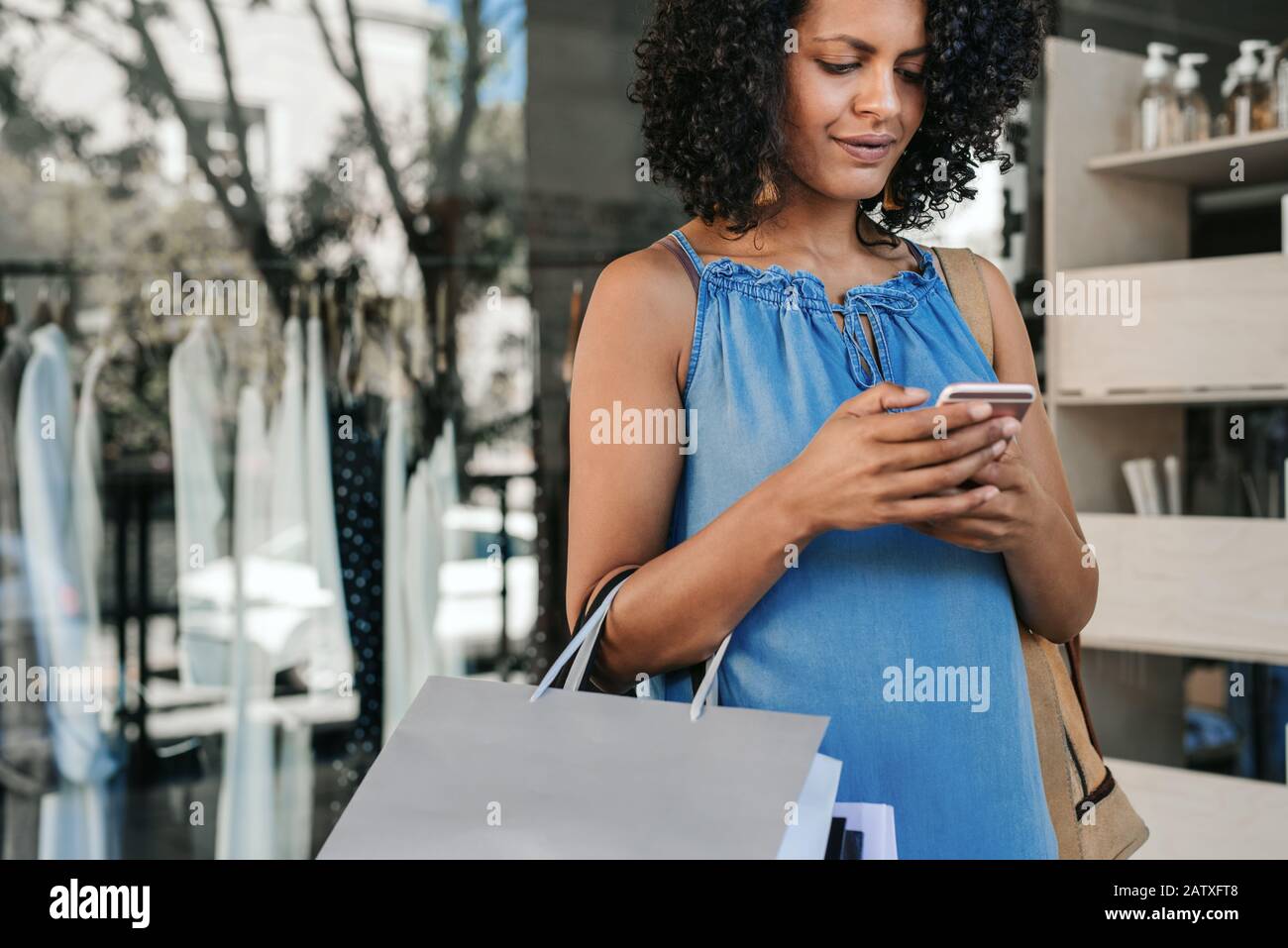 Young woman sending a text message while out clothes shopping Stock Photo