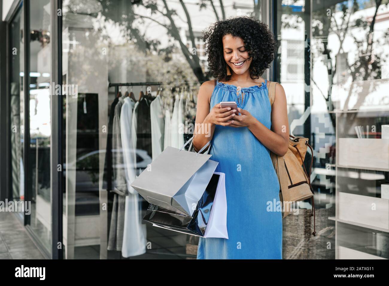 Smiling young woman reading a text while out clothes shopping Stock Photo