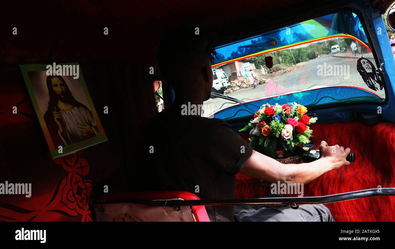 Rickshaw driver with picture of Jesus Christ on the left and Bob Marley on the right Stock Photo