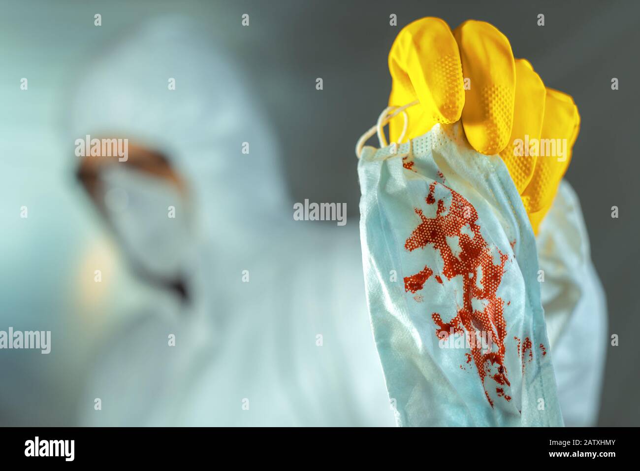 Medical worker disposing bloody protective face respirator mask in quarantine, selective focus Stock Photo