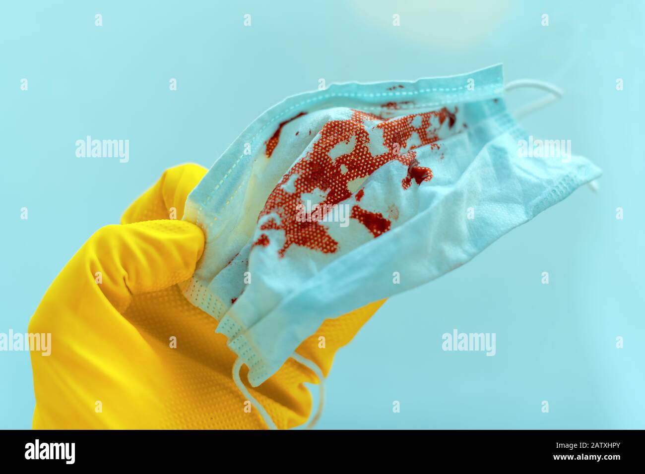 Medical worker disposing bloody protective face respirator mask in quarantine, selective focus Stock Photo