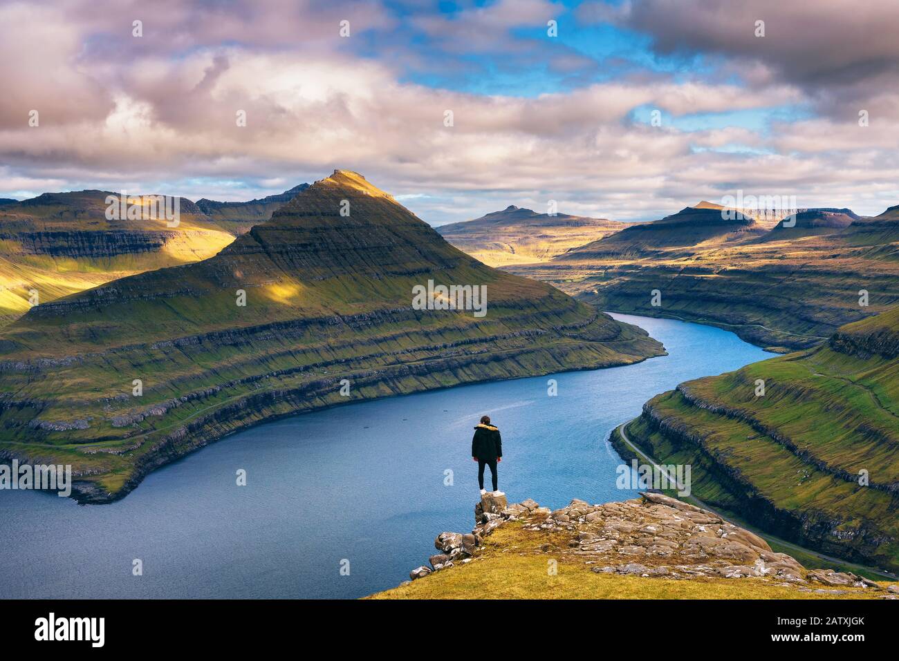 Hiker enjoys views over fjords from a mountain near Funningur on Faroe Islands Stock Photo