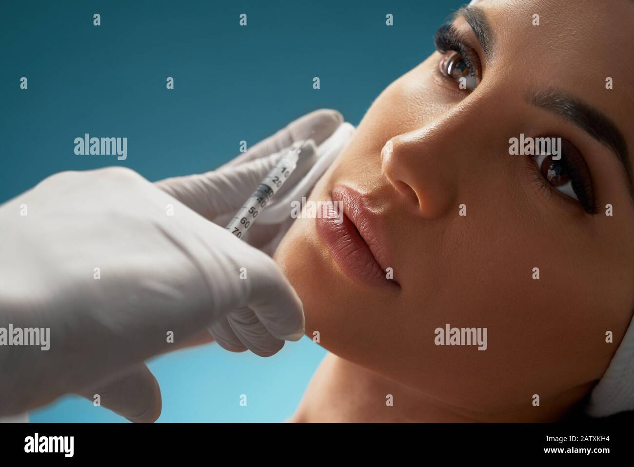 Close up of cosmetic injection in female cheek. Cosmetologist using ...