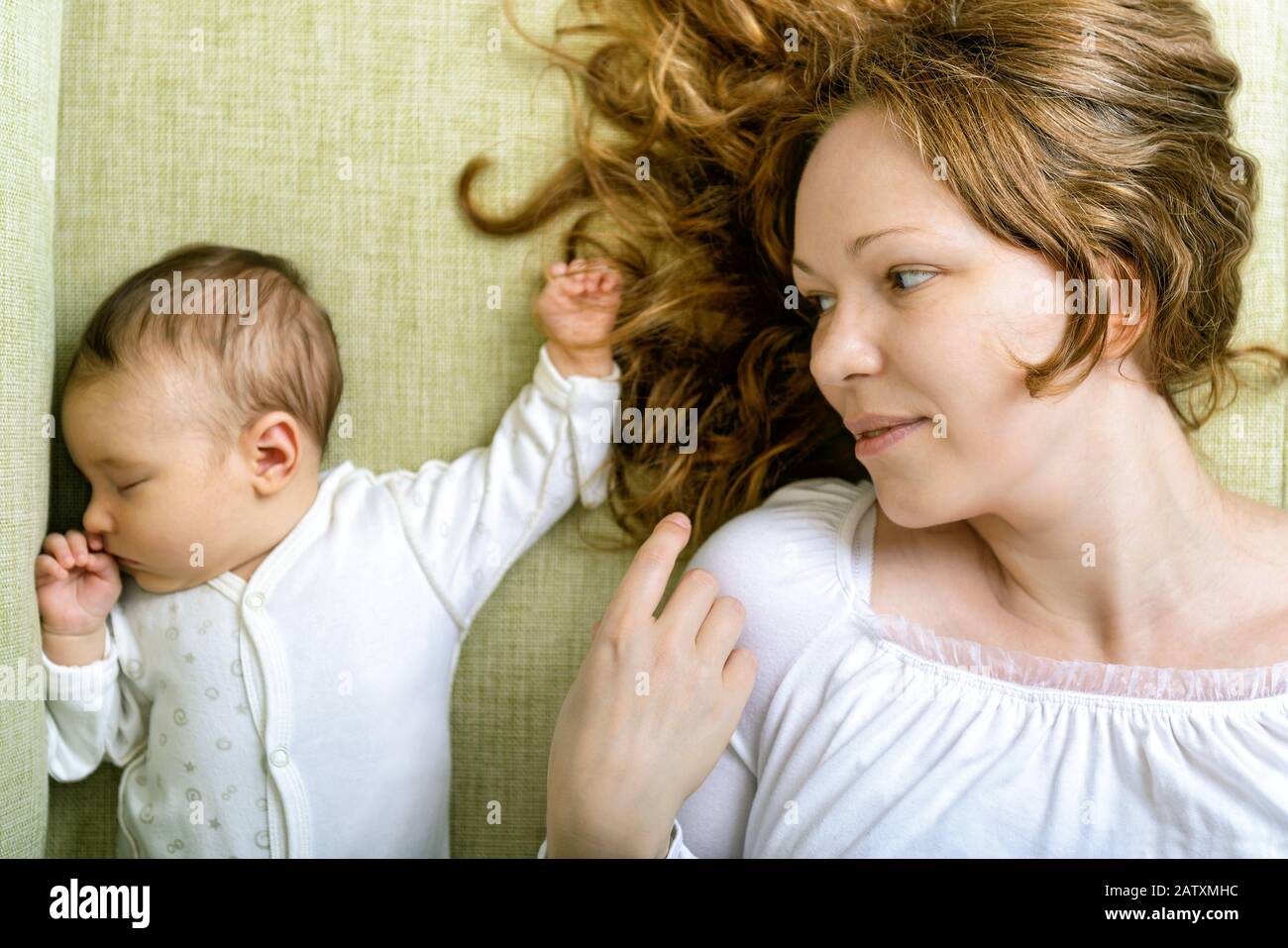 Beautiful woman and her newborn daughter on the couch at home. Stock Photo