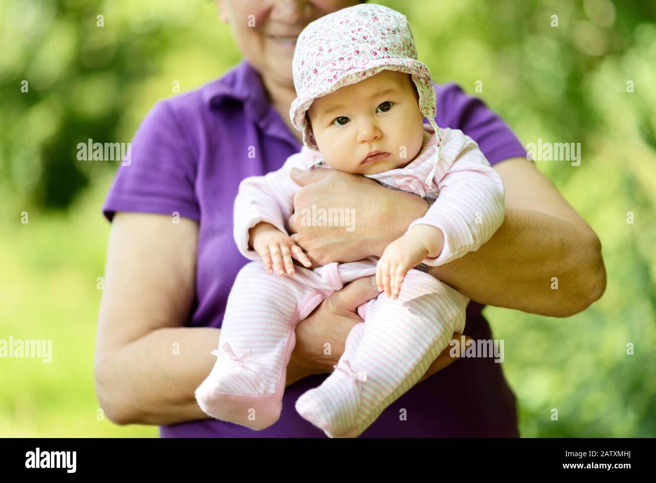 Baby girl on the hands of her grandmother in nature Stock Photo