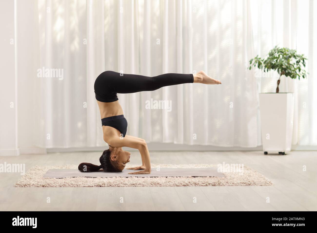 Woman in a yoga studio in a headstand pose - Stock Image - Everypixel