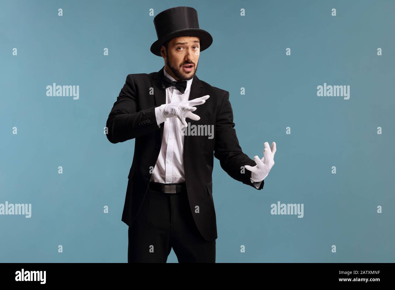 Magician performing a trick with hands isolated on blue background Stock Photo