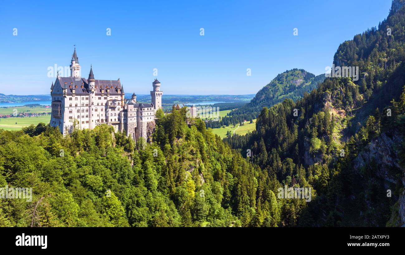Neuschwanstein castle in mountains, Bavaria, Germany. It is a famous landmark of German Alps. Landscape with forest and Neuschwanstein castle in summe Stock Photo
