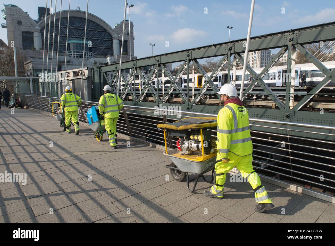 Three building workers carrying heavy equipment in wheelbarrows, Charing Cross, Central London, UK. 3 ouvriers du bâtiment, Londres. Stock Photo