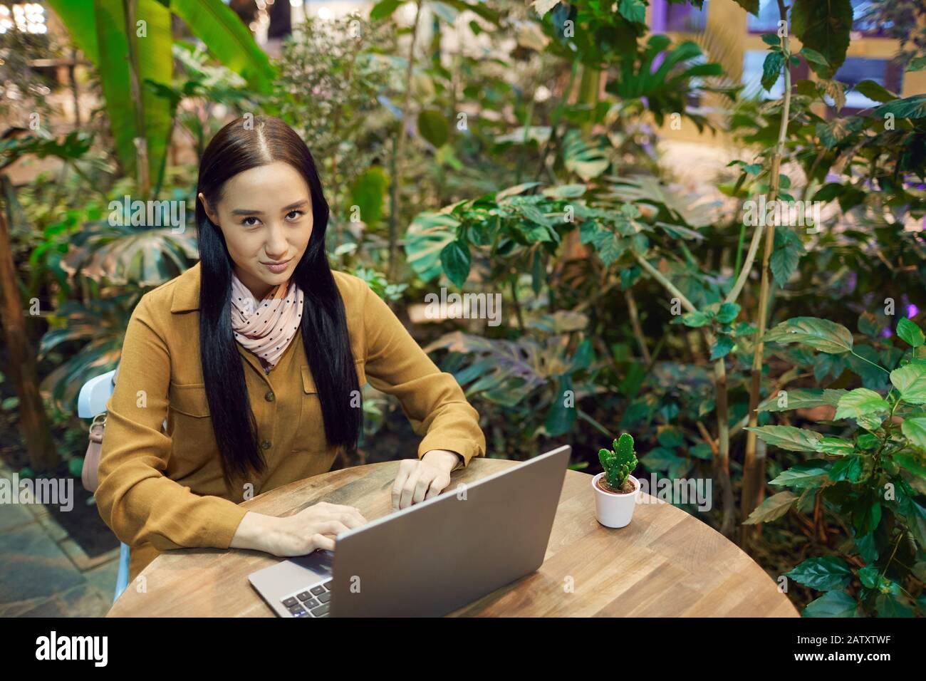 Asian young woman sitting at the table and typing on laptop computer she working online in coffee shop Stock Photo