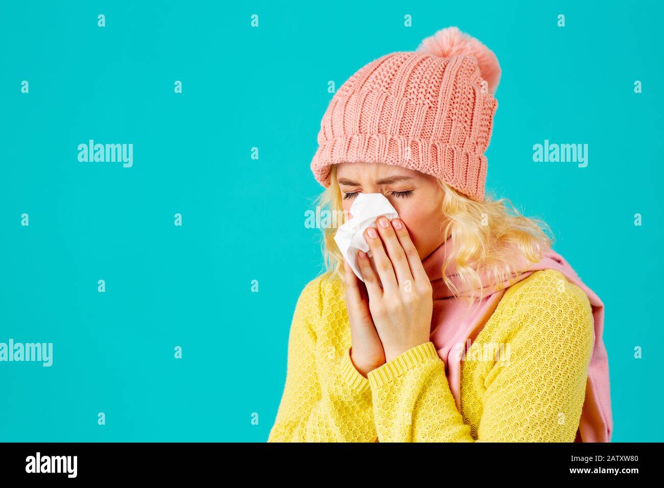 Cold and flu season- portrait of a woman in hat and scarf blowing her nose Stock Photo