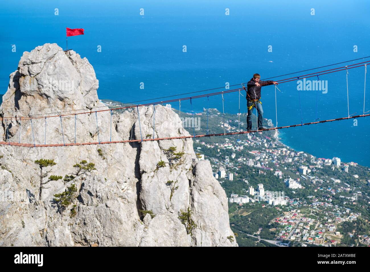 CRIMEA, RUSSIA - MAY 19, 2016: Tourist walking on rope bridge on the Mount Ai-Petri. It is one of the highest mountains in the Crimea and tourist attr Stock Photo