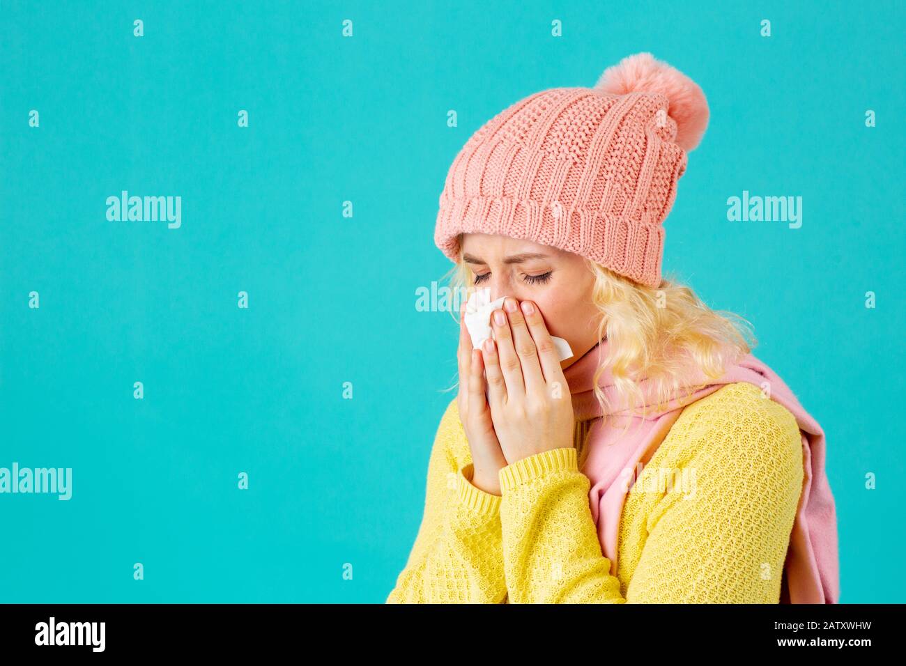 Cold and flu season- portrait of a woman in hat and scarf blowing her nose Stock Photo