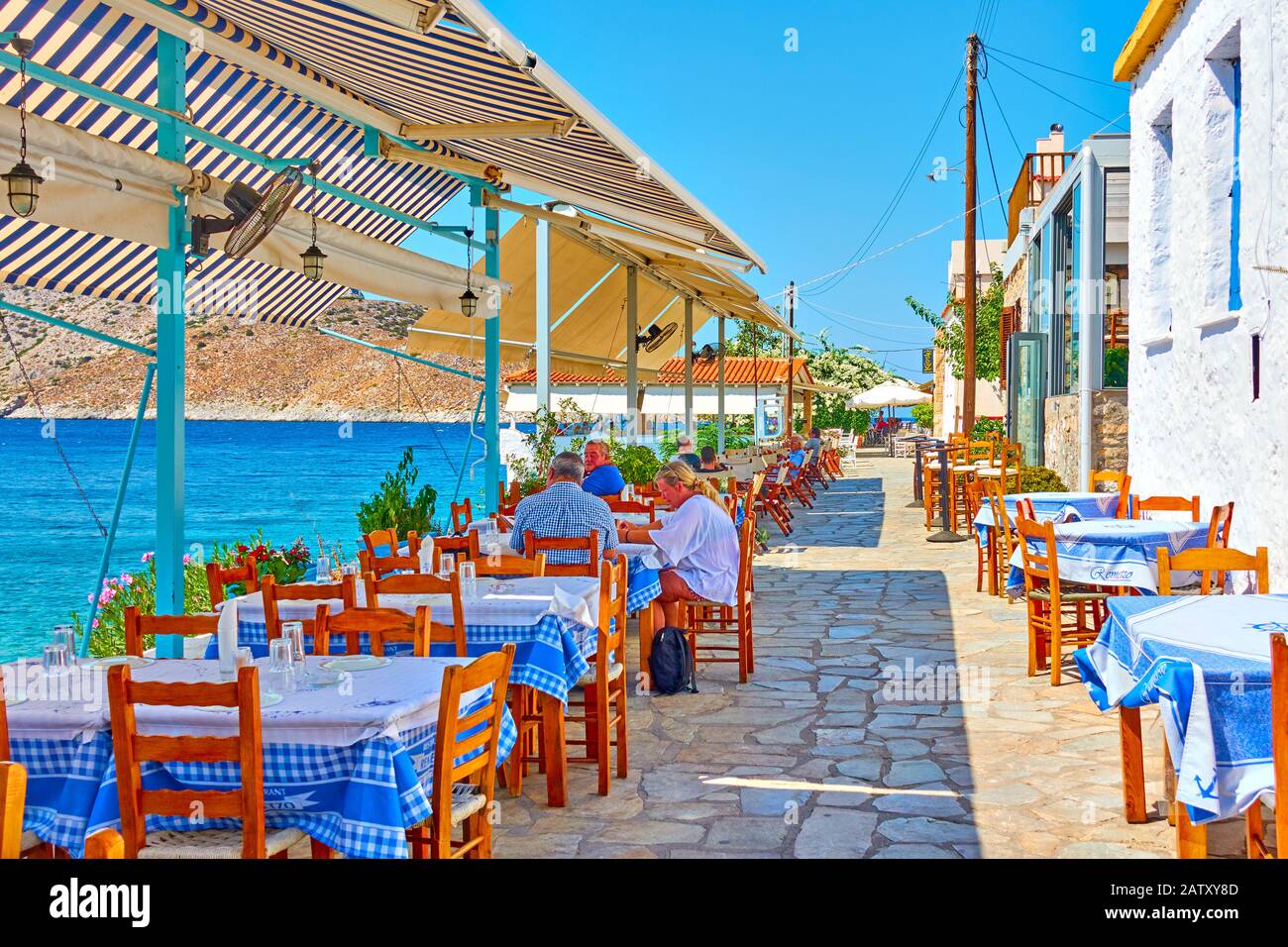 Perdika, Aegina Island, Greece  - September 14, 2019:  Open-air seafood restaurant at waterfront by the sea in Perdika village, Greece Stock Photo